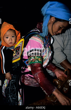 Scena notturna : Donna di Yi minoranza etnica in abito tradizionale, portando il suo bambino sulla schiena. Yunnan, YuanYang. Cina Foto Stock