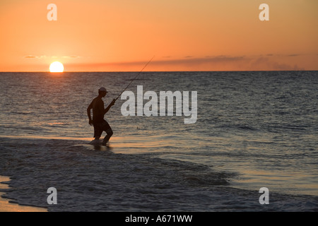 Un pescatori wades nel surf come il sole tramonta su Fraser Island Foto Stock
