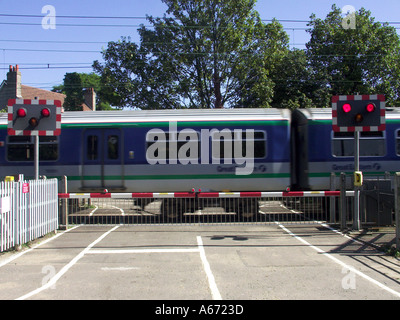 I binari ferroviari rosso lampeggiante spia livello di segno attraversando i cancelli di barriera stradale del paese treni passeggeri motion blur Margaretting Essex England Regno Unito Foto Stock