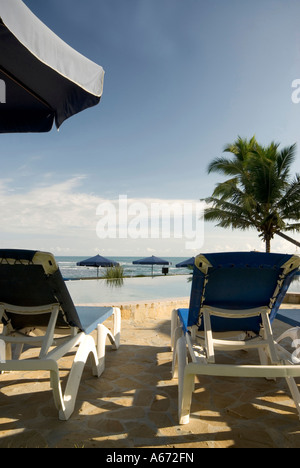 Piscina tropicale lounge charirs chaise infinito dalla spiaggia Foto Stock