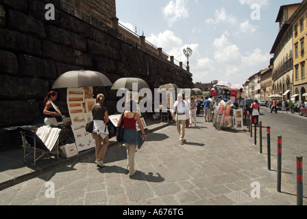 Turisti di Firenze a piedi gli artisti del passato e il loro lavoro in vendita lungo il marciapiede caldo giorno d'estate vicino al Palazzo Pitti Toscana Italia Foto Stock