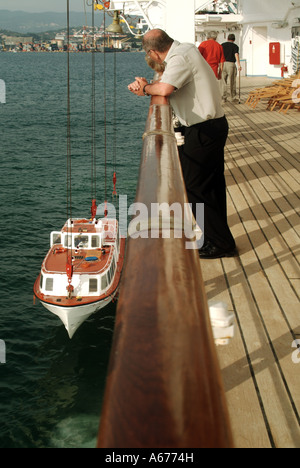 A bordo delle navi da crociera i vacanzieri della camicia sul ponte guarda equipaggio sollevare gara scialuppa di salvataggio dal mare dopo il ritorno di passeggeri da viaggio shore a La Spezia in Italia Foto Stock