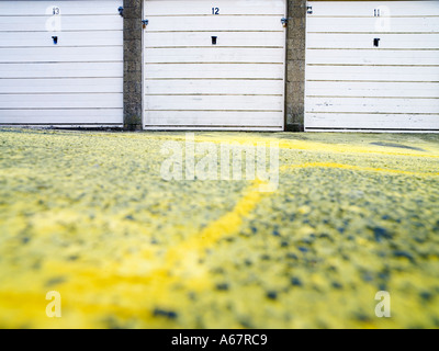 Una fila di tre numerate da porte di garage vernice gialla sulla terra nella parte anteriore Foto Stock