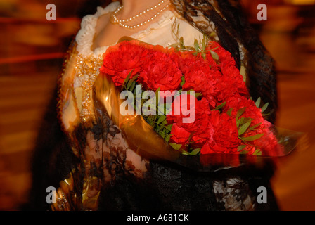 Reveler in abbigliamento tradizionale azienda bouquet di rose rosse fiori durante il periodo del festival Las Fallas a Valencia Spagna Foto Stock