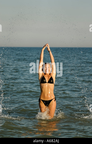 Giovane donna salta in acqua Foto Stock