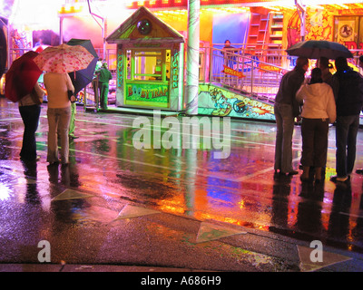 Fairground Ride con box office riflessa nel pavimento bagnato Foto Stock