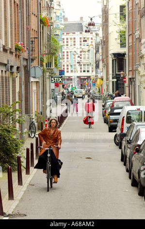 Ciclisti su una strada tranquilla nel centro di Amsterdam, con auto parcheggiate lungo il marciapiede. Paesi Bassi Foto Stock