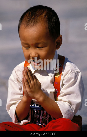 Cina, Pechino, ragazzo giovane con le mani piegate Foto Stock