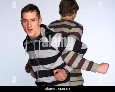 Due uomini che indossano identiche striata tops standing schiena a schiena con le loro braccia interbloccati Foto Stock