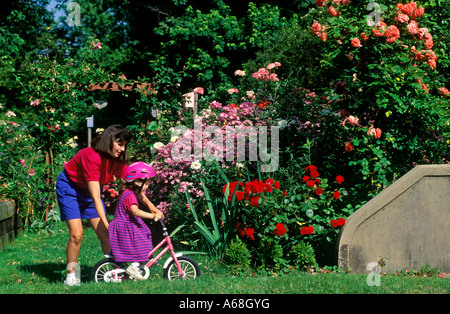 Madre figlia aiuta a imparare ad andare in bicicletta Foto Stock