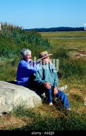 Coppia di anziani di condividere un momento seduto sulla roccia di grandi dimensioni Foto Stock