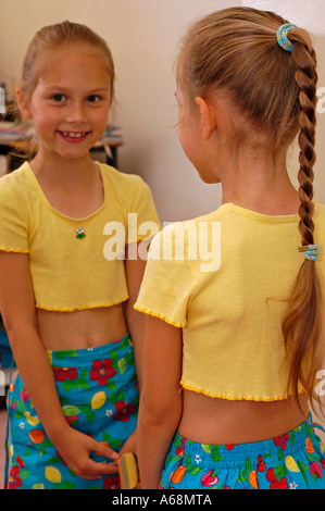 Una giovane ragazza bionda di fronte a uno specchio Foto Stock