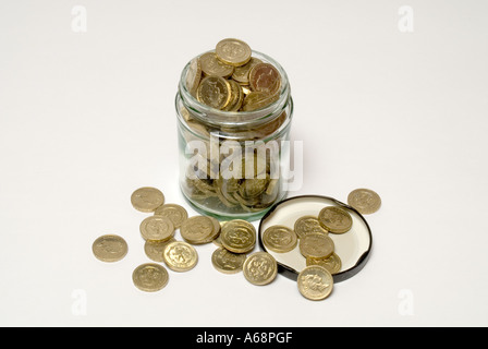 Immagazzinando e risparmiando una libbra valuta di soldi di sterlina in un vaso overflow della marmellata sicuro per un giorno piovoso in Inghilterra Regno Unito Foto Stock