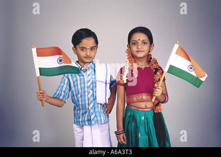 Sud indiana ragazza ragazzo che indossa abiti fantasiosi costumi tradizionali tenendo la bandiera indiana Foto Stock