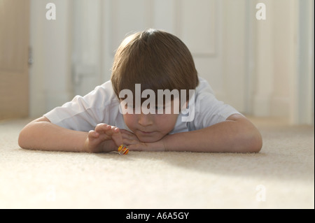 Ragazzo giocando marmi a casa sdraiato su un tappeto Foto Stock