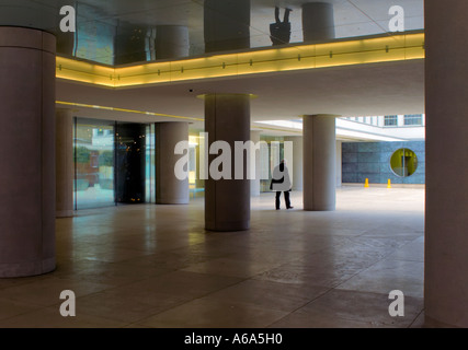 Isolato la figura di uomo a camminare attraverso colonne al di fuori di un edificio moderno Foto Stock