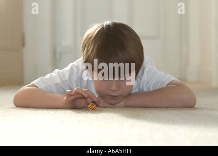 Ragazzo giocando marmi sdraiato sul tappeto Foto Stock