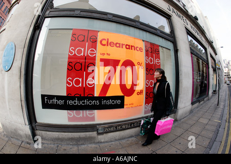 Le vendite in Cardiff giovane donna camminare davanti a un segno di vendita a James Howell e Co Ltd Foto Stock