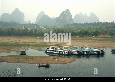 La Cina, nel Guangxi, Yangshuo, traghetti ormeggiati lungo Li Jiang (Fiume Li), con fengcong colline carsiche di risalita in distanza Foto Stock