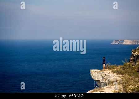 Uomo che guarda l'orizzonte dal bordo di una scogliera isola di Lampedusa sicilia italia Foto Stock