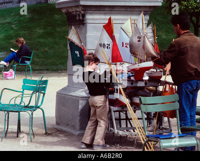 Francia Parigi. Barche a vela giocattolo ai Giardini di Lussemburgo, Jardin des Tuileries, un ragazzo giovane che seleziona un giocattolo a vela a noleggio. Bambini nel parco Foto Stock