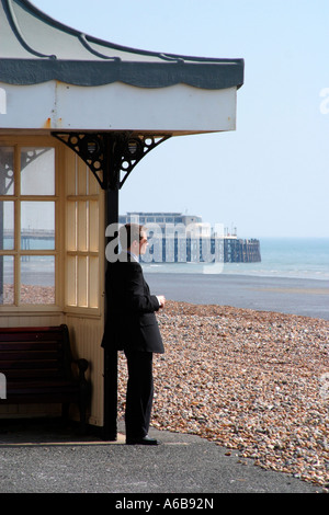 Un uomo d'affari sulla spiaggia che guarda al mare a Worthing, West Sussex, UK Foto Stock
