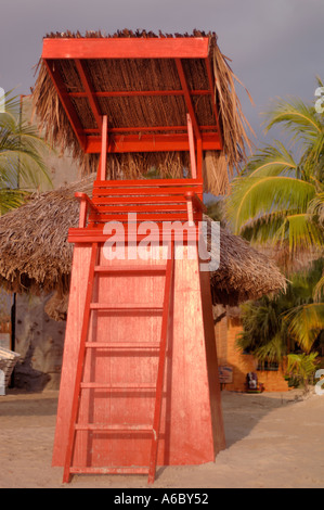 Un colore dell'immagine in verticale di un arancione lifegaurd sedia con un tetto di paglia nel tardo pomeriggio l'illuminazione Foto Stock