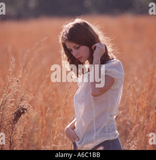 pensive young woman walking alone in field Foto Stock