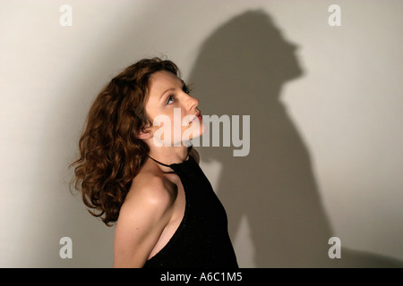 Attraente giovane donna vestita di nero vestito con ombra su sfondo Foto Stock