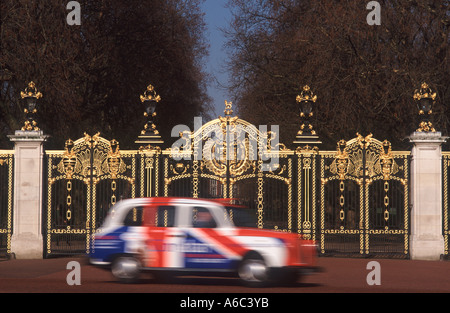 Union Jack London dipinte di cabina in movimento sfocato passando oro e nero ferro battuto del Canada Gate, Green Park, Londra Foto Stock