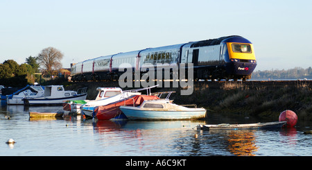 Barche ormeggiate in porto Cockwood tra Dawlish Warren e Starcross presso sunrise con un primo grande Western treno Intercity Foto Stock