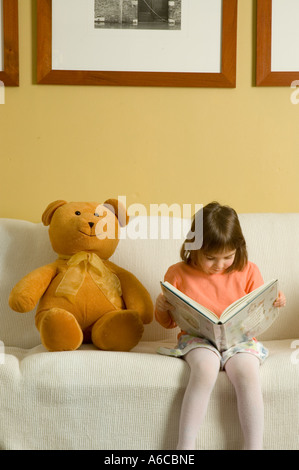 Giovani cinque anno ragazza seduta verso il basso per una lettura dal suo libro preferito Foto Stock