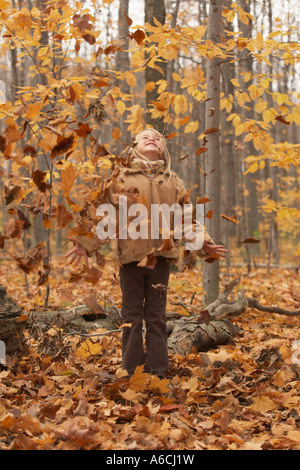 Ragazza in piedi in foglie di autunno Foto Stock