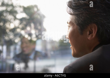 Imprenditore a guardare fuori dalla finestra Foto Stock