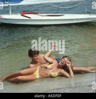 Giovane che giace sulla spiaggia sabbiosa spiaggia di ridere Foto Stock