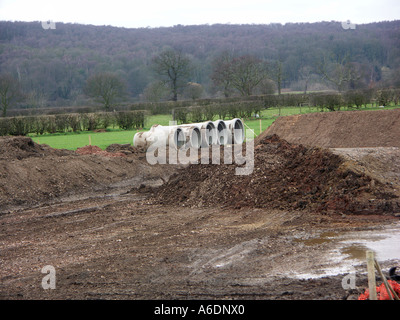 Grande pre-getto di calcestruzzo rete fognaria o tubi di drenaggio su un campo verde di costruzione o di cantiere. Foto Stock