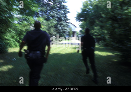 Detroit funzionari di polizia inseguire un sospetto in una corsa verso il basso quartiere di Detroit Foto Stock