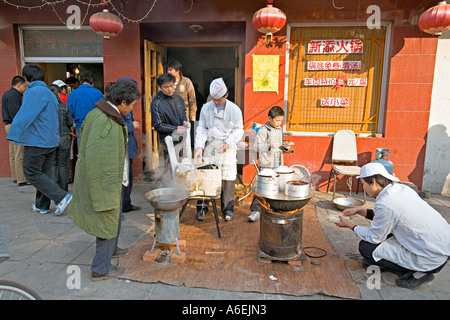 Cina Pechino minuscolo ma occupato quartiere ristorante con chef impostato sul marciapiede per preparare la colazione gnocchi Foto Stock