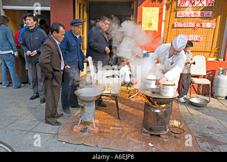 Cina Pechino minuscolo ma occupato quartiere ristorante con chef impostato sul marciapiede per preparare la colazione gnocchi Foto Stock