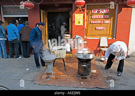 Cina Pechino minuscolo ma occupato quartiere ristorante con chef impostato sul marciapiede per preparare la colazione gnocchi di uova sode Foto Stock