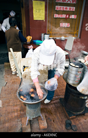 Cina Pechino minuscolo ma occupato quartiere ristorante con chef impostato sul marciapiede per preparare la colazione gnocchi di uova sode Foto Stock