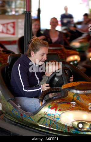 Madre e figlio di piccole dimensioni che si divertono sull'dodgem auto a una fiera. Foto Stock