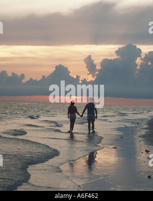 Giovane camminando sulla spiaggia al tramonto Foto Stock