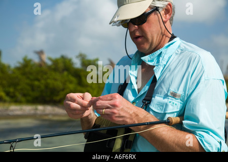 BELIZE Ambergris Caye maschi adulti per la pesca con la mosca in appartamenti lungo il litorale per bonefish cambiare volare sulla linea nodo di cravatta Foto Stock