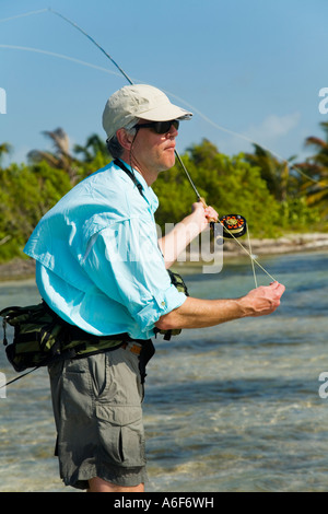 BELIZE Ambergris Caye maschi adulti per la pesca con la mosca in appartamenti lungo il litorale per bonefish casting Rod Reel e la lenza in mano Foto Stock