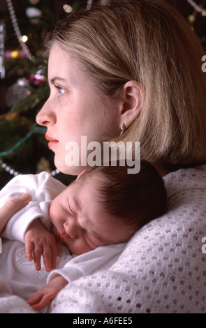 Ventiquattro 24 anni vecchia madre con cinque di 5 settimane di età bambino accanto a albero di Natale la mamma ha gravi pensieroso cupo espressione pensosa England Regno Unito Foto Stock