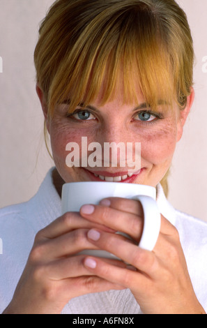 Donna sorseggiate una tazza bianca Foto Stock