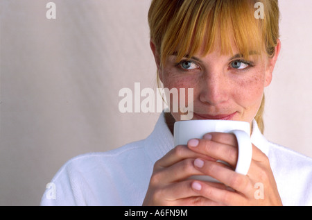 Donna sorseggiate una tazza bianca Foto Stock