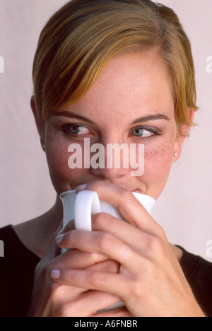 Donna sorseggiate una tazza bianca Foto Stock