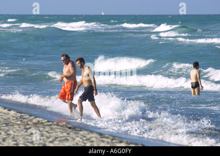 MIAMI BEACH FLORIDA USA due uomini a piedi attraverso il surf sulle spiagge di South Beach Foto Stock